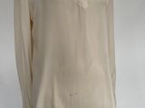beige shirt on a mannequin stand in front of a white backdrop