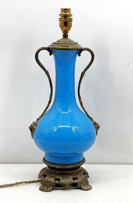 un vase bleu posé sur un socle, auquel est attachée une chaîne