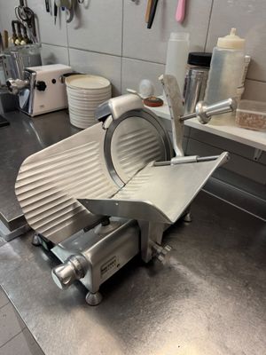 an image of a kitchen with a meat slicer on the counter
