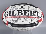 a signed rugby ball on display on a clear stand