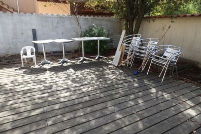 une table et des chaises blanches sur une terrasse en bois
