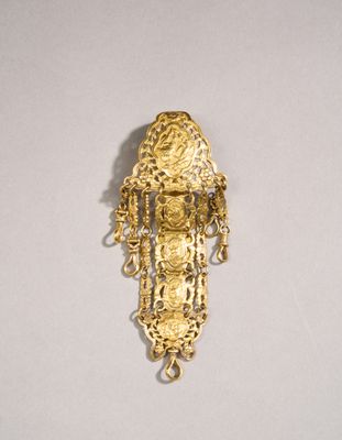 une image représentant une broche plaquée or, ornée de chaînes et de perles
