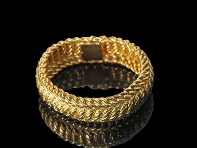 gros plan d'un bracelet en or sur une surface noire