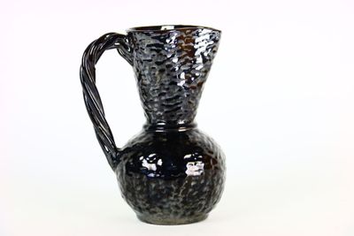 un vase noir posé sur une surface blanche