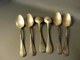 five spoons are lined up in a row on a table