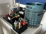 a desk with a basket of pens and pencils on it