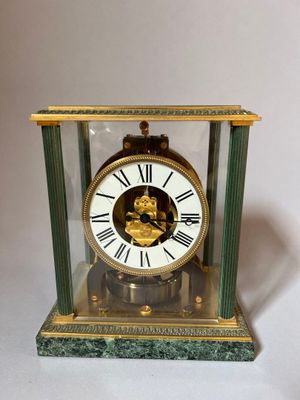 a clock that is sitting in a glass case on a table