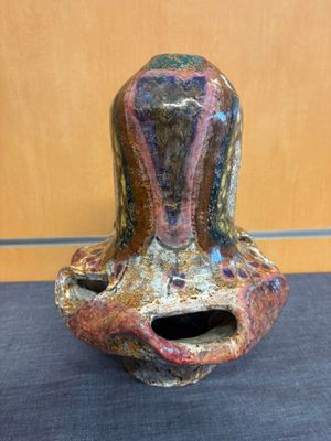 un vase coloré percé d'un trou, posé sur une table