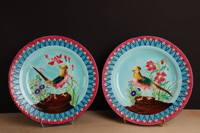 two plates with birds painted on them sitting on a table