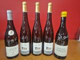 six bouteilles de vin sont alignées sur une table en bois