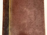 un gros plan d'un livre marron posé sur une surface blanche