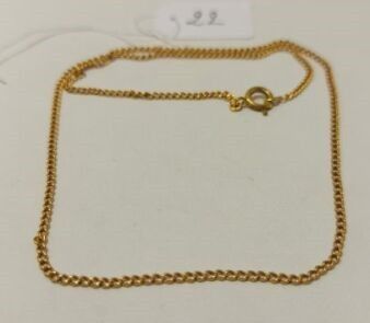 gros plan d'un bracelet en chaîne en or sur une surface blanche