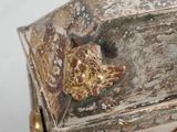 a silver and gold box with a face on it