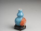 a small blue and orange vase sitting on a black stand