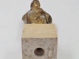statue of a man sitting on a block with a small hole in the middle of it