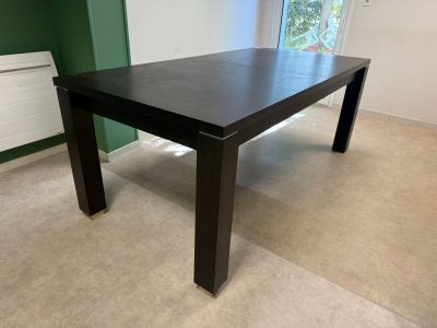 une table noire dans une pièce où se trouve un radiateur dans un coin