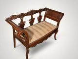 an old wooden bench with a striped seat cushion on it
