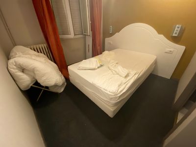 a white bed in a small room with a red curtain