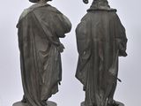 three bronze statues of men standing next to each other on a white surface