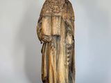 an old wooden statue of a man holding a book