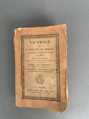 un vieux livre posé sur une table à côté d'un mur