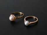 two gold rings with pearls on them on a black surface