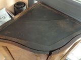 an old wooden cabinet with a black top next to a window
