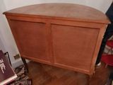 a wooden cabinet with a door on top of a hard wood floor