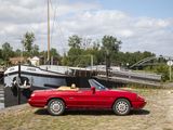 a red sports car parked next to a boat on the water