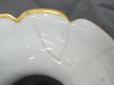 a white vase with a gold edge on a gray surface