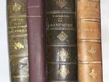 several old books are lined up on a shelf next to each other