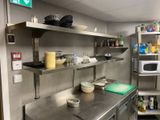 a kitchen with stainless steel shelves and a microwave on the wall