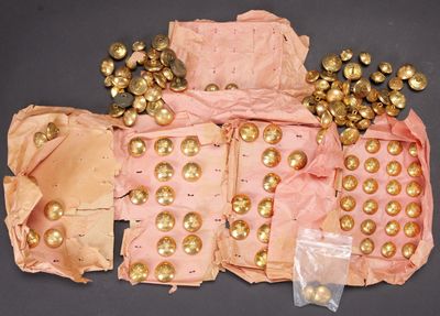 un sac rose avec des boutons dorés et un tas de boules dorées