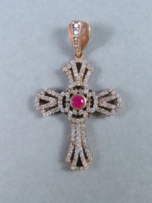 un gros plan d'un pendentif en forme de croix en diamant posé sur une surface blanche