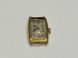 a small gold watch sitting on a white surface