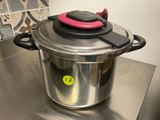 une casserole en inox avec un couvercle rose posée sur un plan de travail
