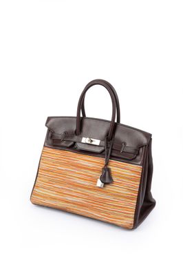 a brown and orange striped handbag sitting on top of a white surface
