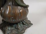 a bronze statue of a woman holding a flower