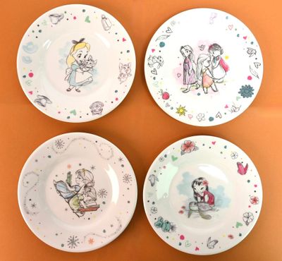 quatre assiettes ornées de personnages de dessins animés, sur un fond orange