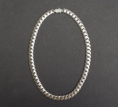 un collier à chaîne en argent posé sur une surface noire