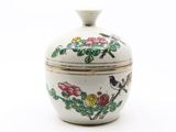 un petit vase blanc orné d'un oiseau et de fleurs