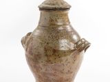 a brown vase with a lid sitting on a white surface