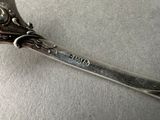 a silver spoon with a flower on it sitting on a table