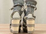 pair of women ' s gray sandals on a wooden table with a curtain in the background