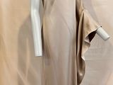 une photo d'un mannequin portant une robe beige, posé sur un socle