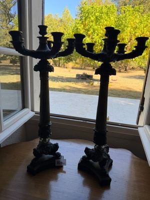 two black candelabs on a table in front of a window