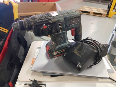 a corded drill sitting on top of a laptop computer