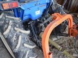 a tractor with a plow attached to it ' s front wheel
