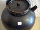 un pot noir posé sur une table, avec une étiquette dessus