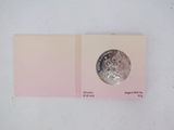 an open book with a silver coin on top of it
